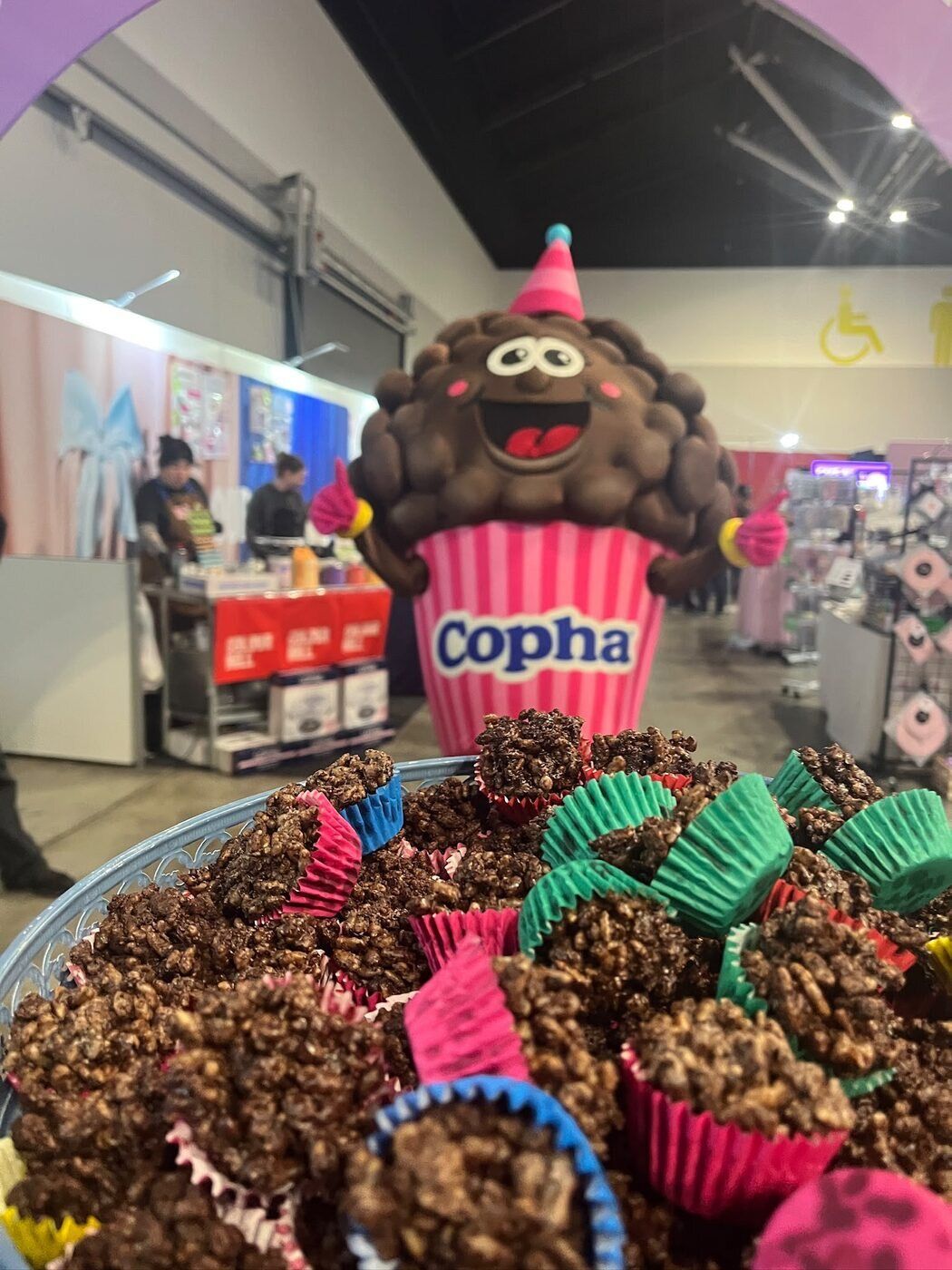 Coral Crackle, Copha's chocolate crackle mascot, beside a tray of mini chocolate crackles