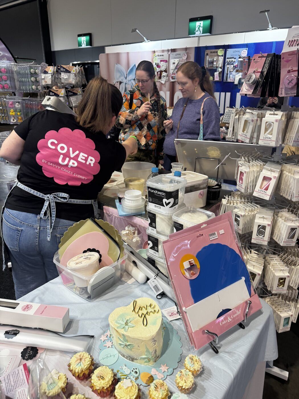 A decorated cake and cupcakes on display at the Cover Up stand