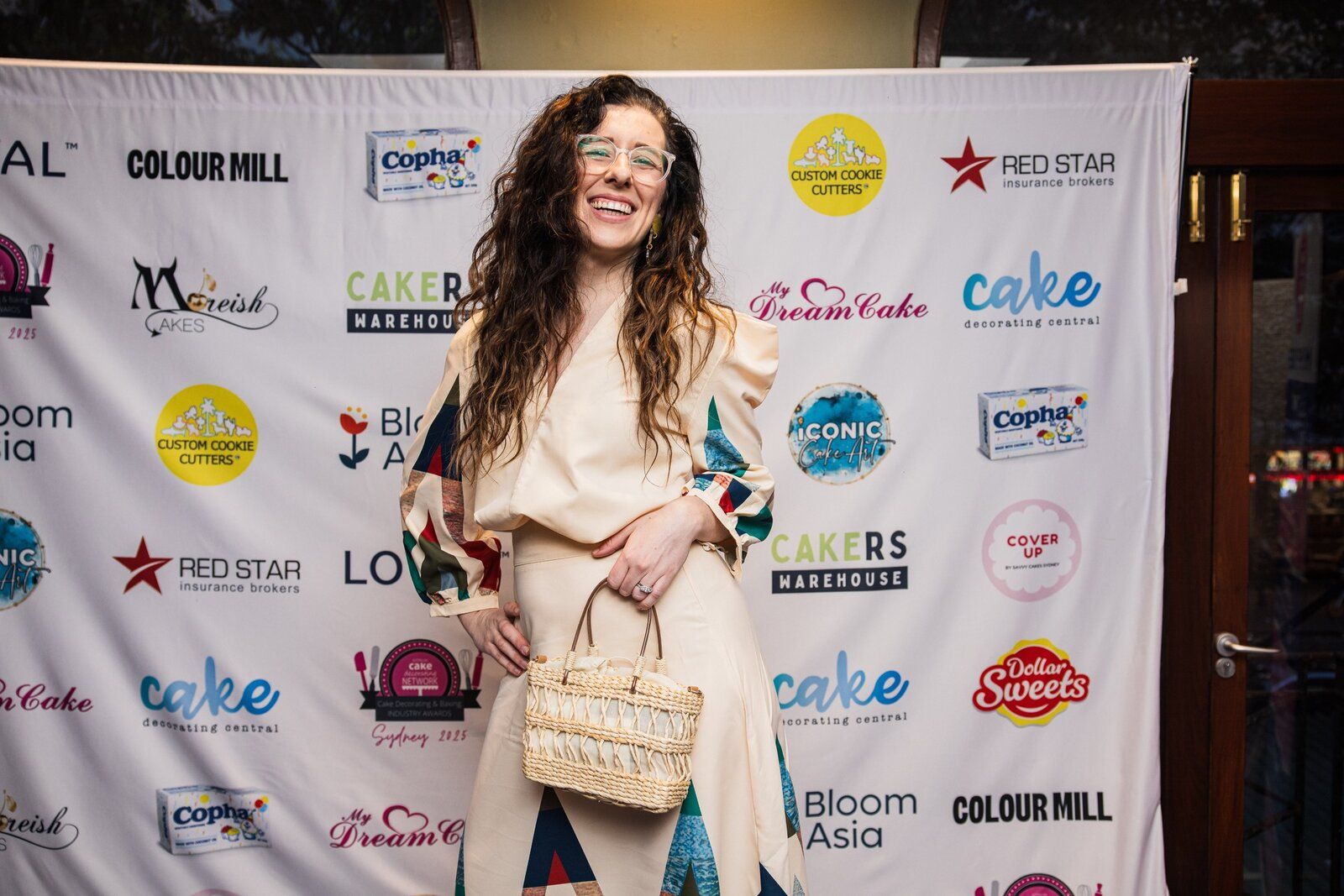 A guest laughing as she poses in front of the sponsor banner at the 2025 ACDN Awards Night