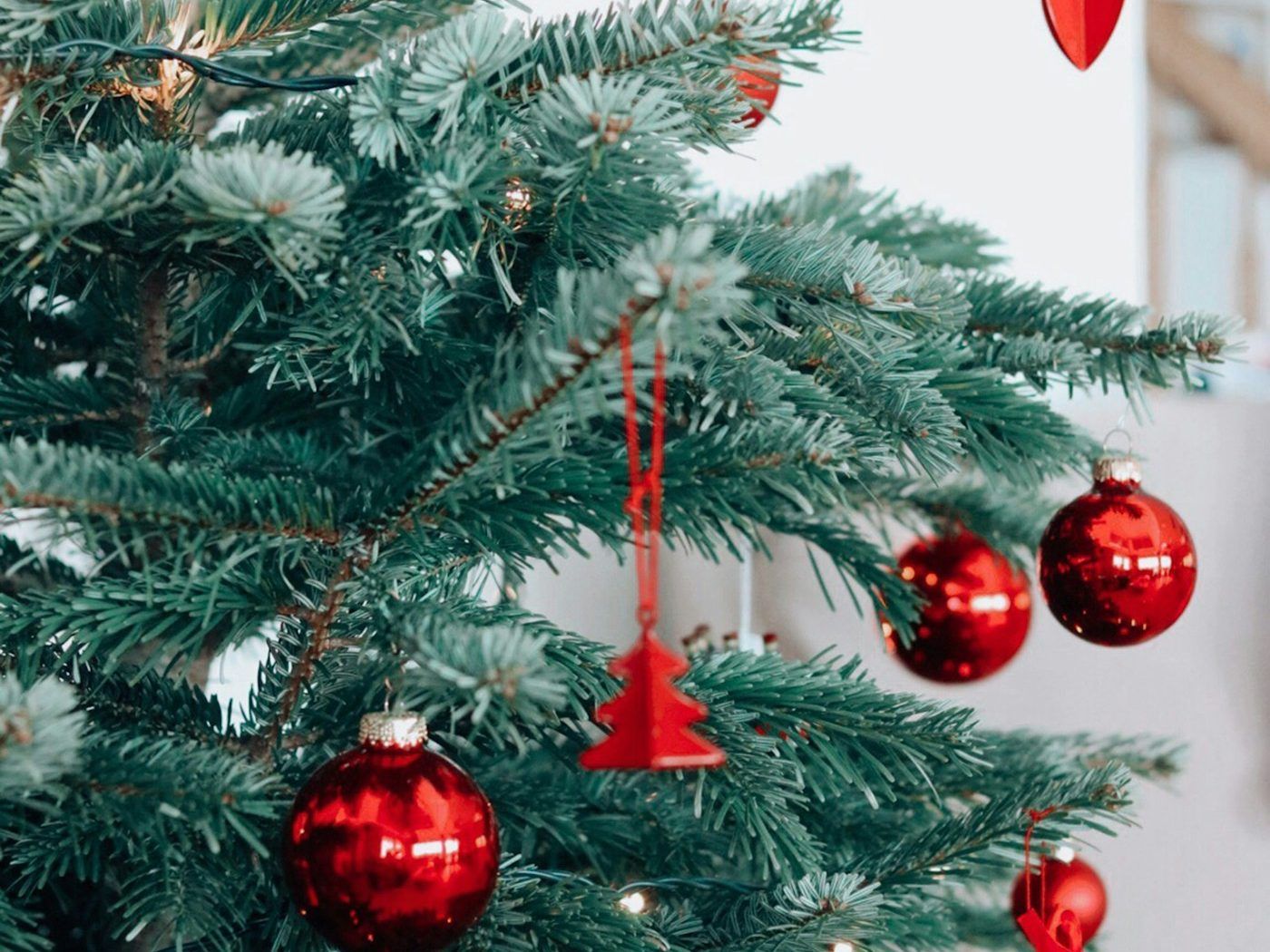 Red baubles and a bell hanging on a Christmas tree