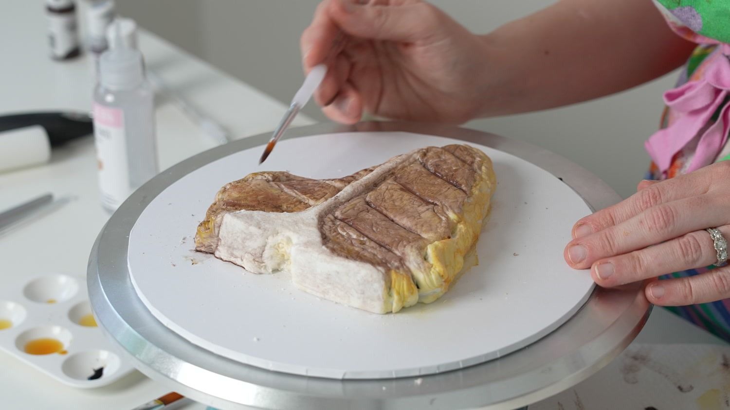 Hand-painting char colour onto a sponge cake shaped like a T-bone steak