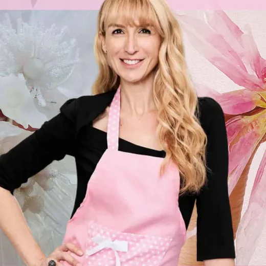 Monica Cavallaro in a pink apron, with large wafer paper flowers either side of her